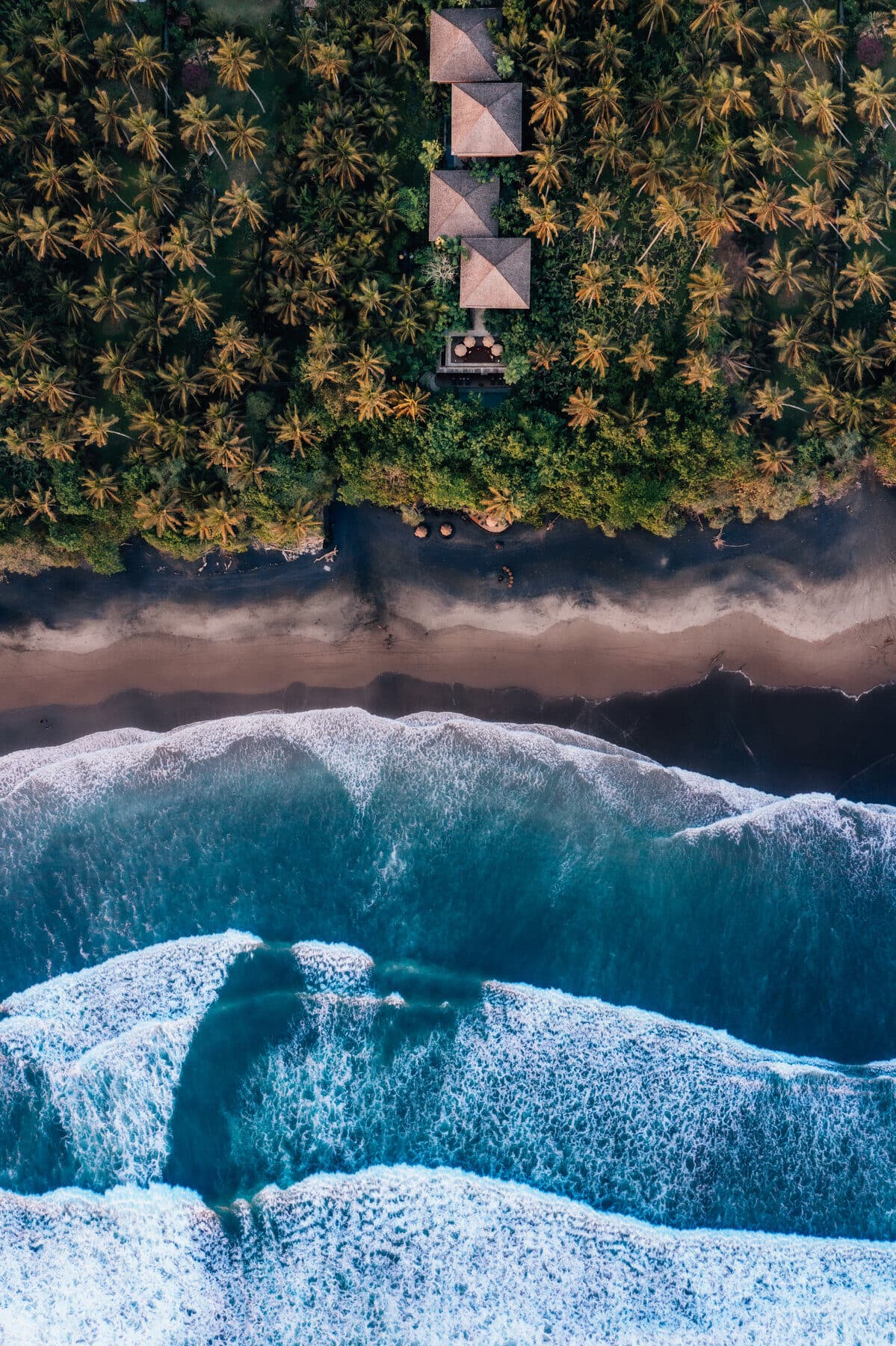 Aerial view of Bali coastline with waves and jungle villas